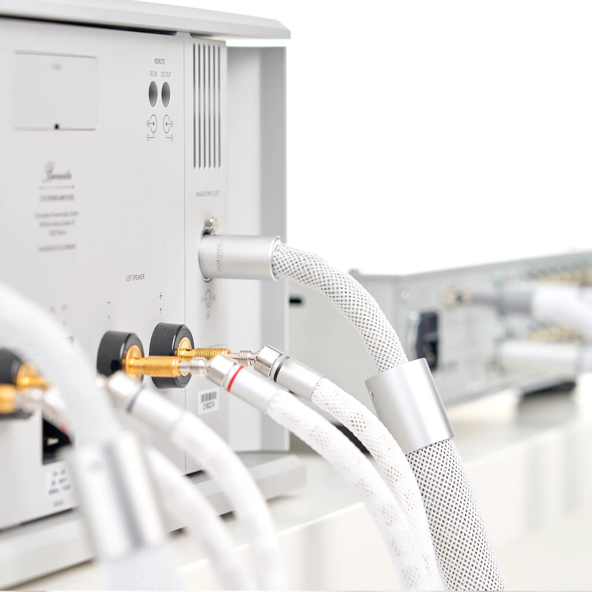 Rückseite eines silbernen LS-2405-Geräts mit mehreren angeschlossenen weißen Audiokabeln und einem dicken, geflochtenen Kabel
