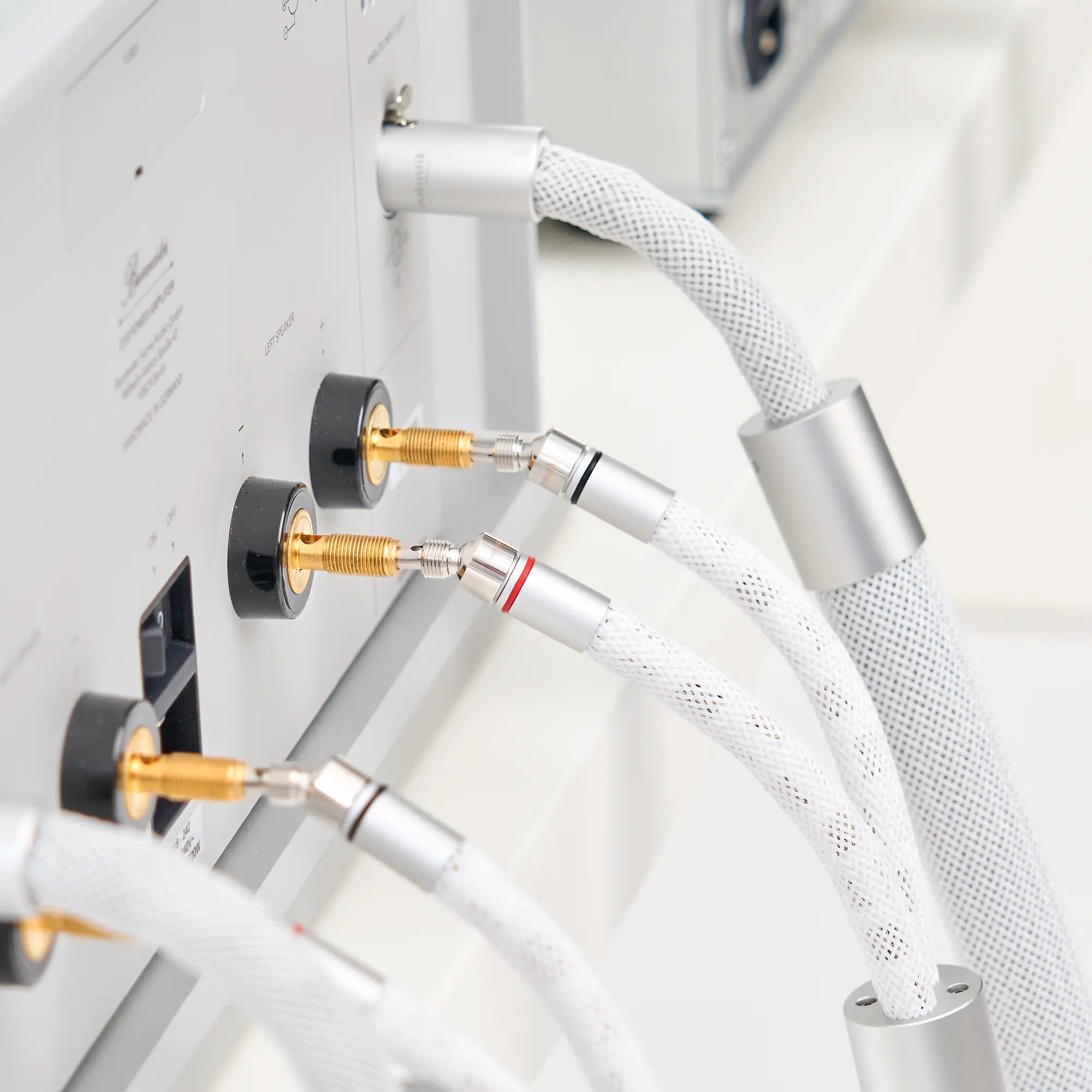 Rückseite eines silbernen LS-2405-Geräts mit mehreren angeschlossenen weißen Audiokabeln und einem dicken, geflochtenen Kabel